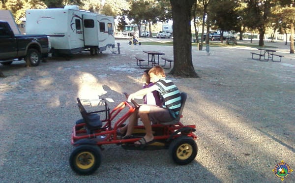 2 kids riding a petal bike around a campground