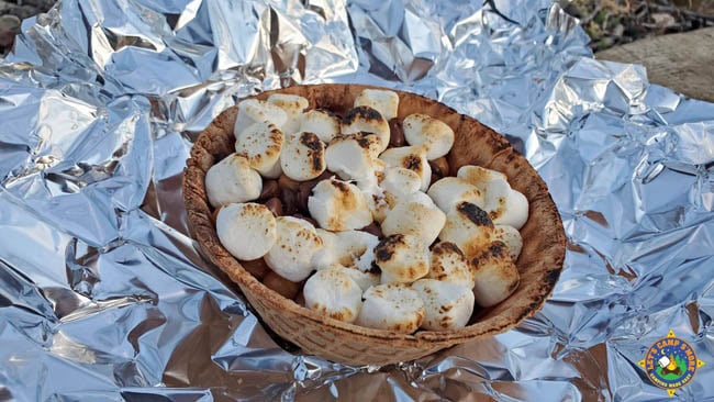 a waffle bowl filled with s'more fixings laying on a piece of foil