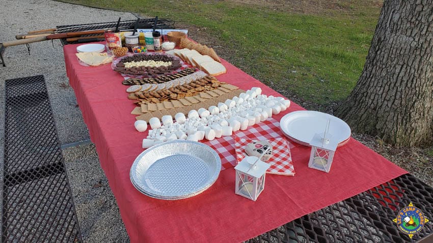 s'more charcuterie board set up on a picnic table at a campground