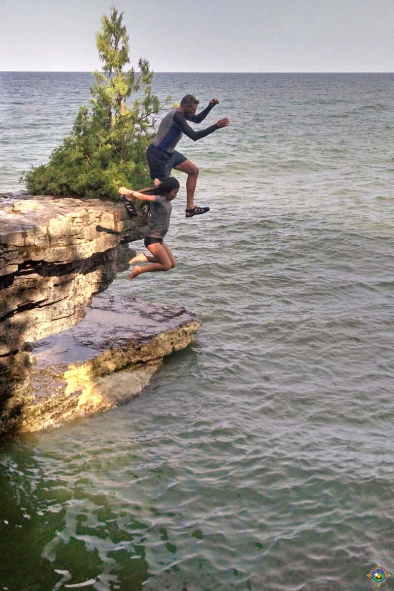 Two people Cliff Jumping into Lake Michigan at Cave Point County Park in Door County