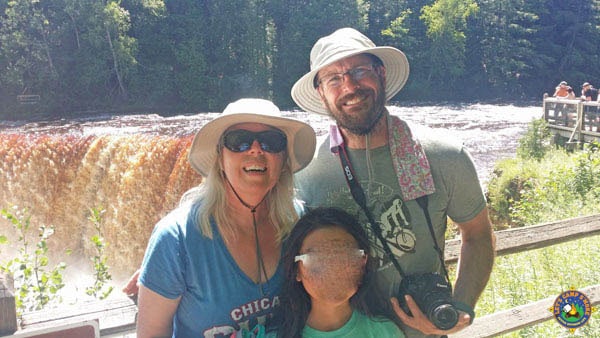 family posing at the edge of Tahquamenon Falls