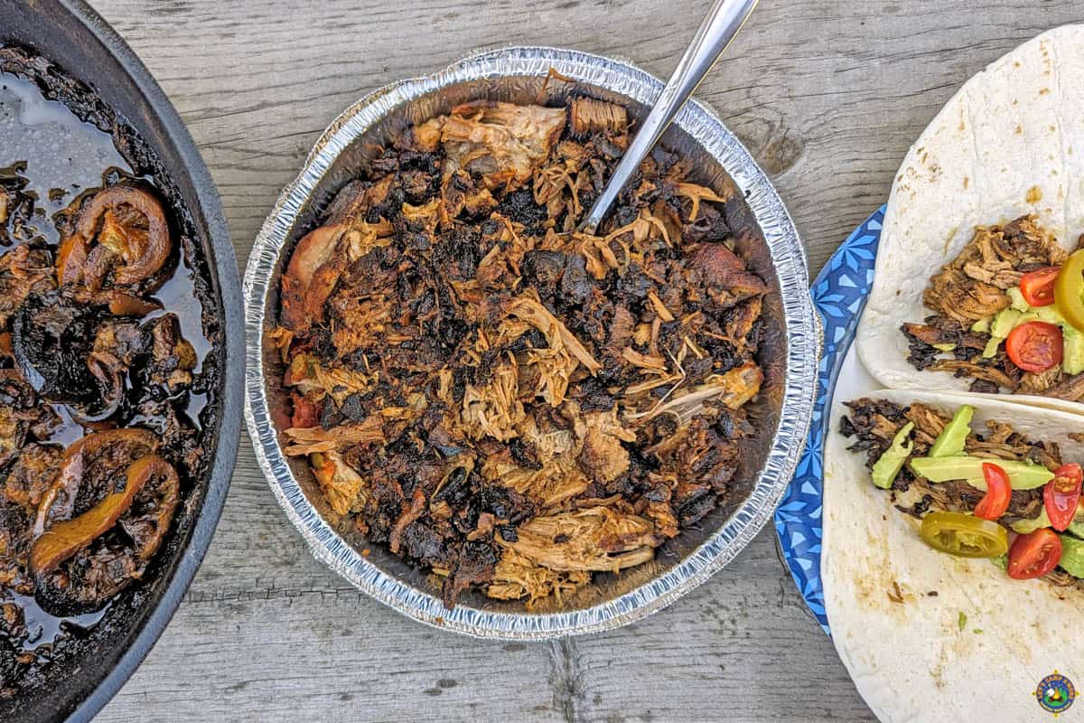 Pork Carnitas in a Dutch Oven with pulled pork in a pan and tacos