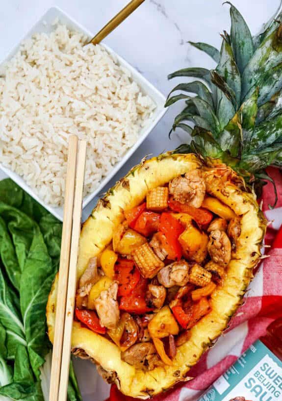 stir fry in half a pineapple with a side of rice