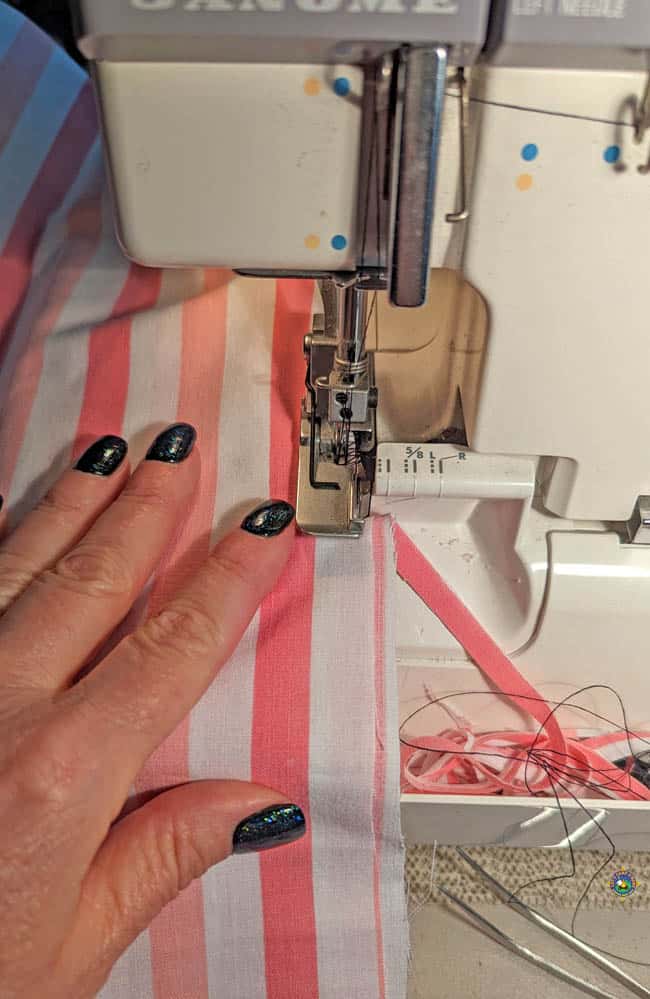 close up of a hand holding material in a sewing serger machine