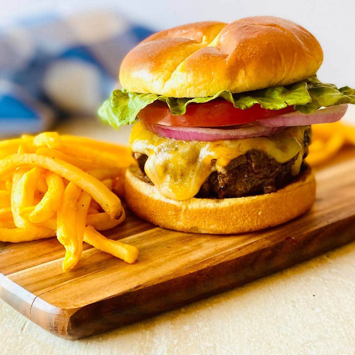 smash burger on a board with a side of french fries