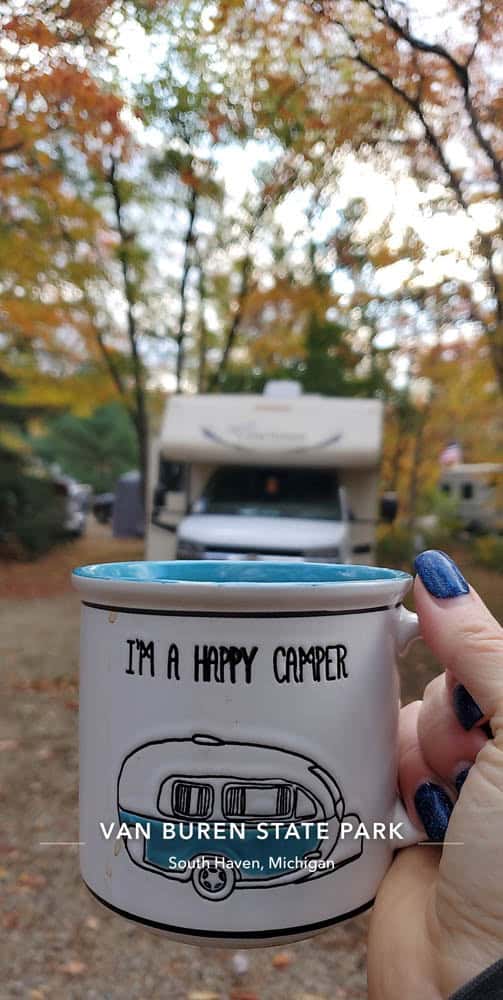 Happy Camper mug held with a camper in the background