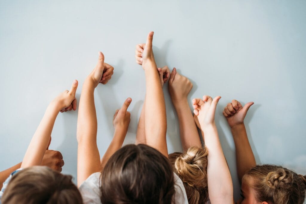 back view of group of kids showing thumbs up