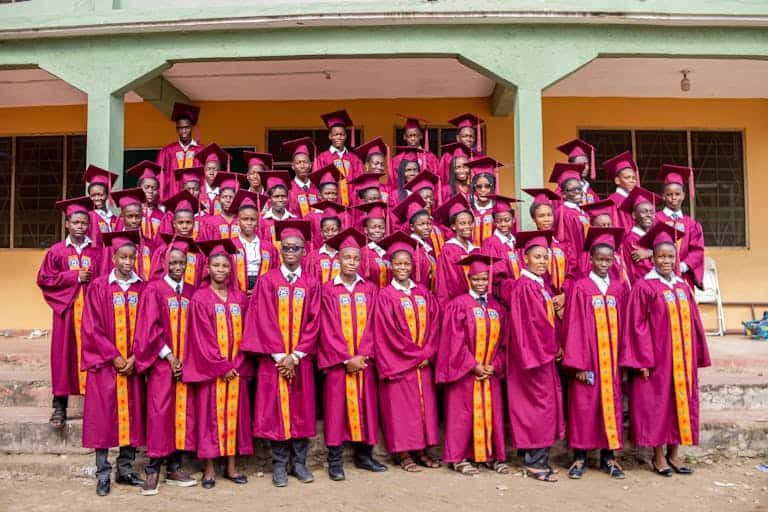 A group of graduates in burgundy gowns celebrating their ceremony in Winneba, Ghana.