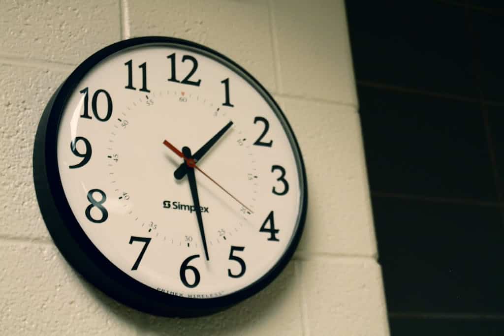 Simplex wall clock on a white brick wall, depicting time and simplicity.
