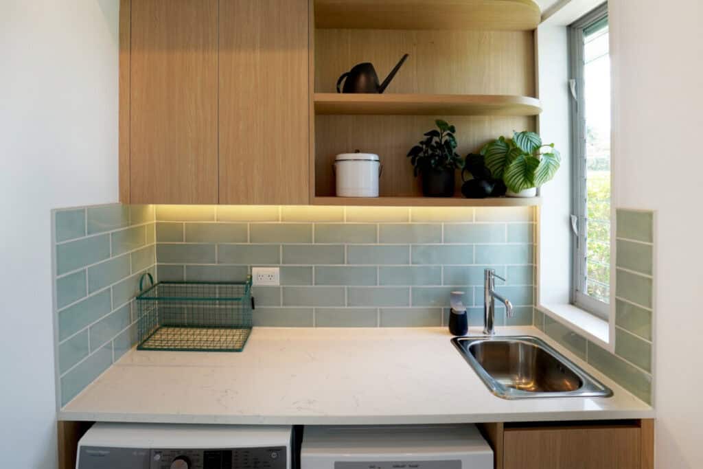 Custom Little Giant Interiors laundry cabinetry with full-height storage and integrated appliances