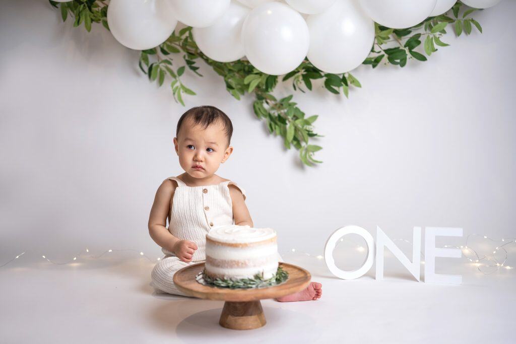 Minimalist cake smash setup with white balloons, simple decor, and a clean background in an Edmonton studio.