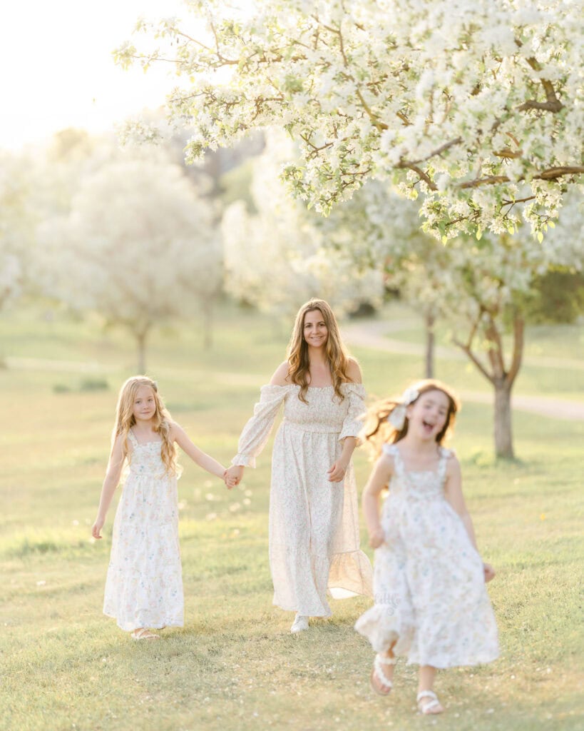 Mom and her 2 dauthers running under blossom tree s in Edmonton for spring family photoshoot