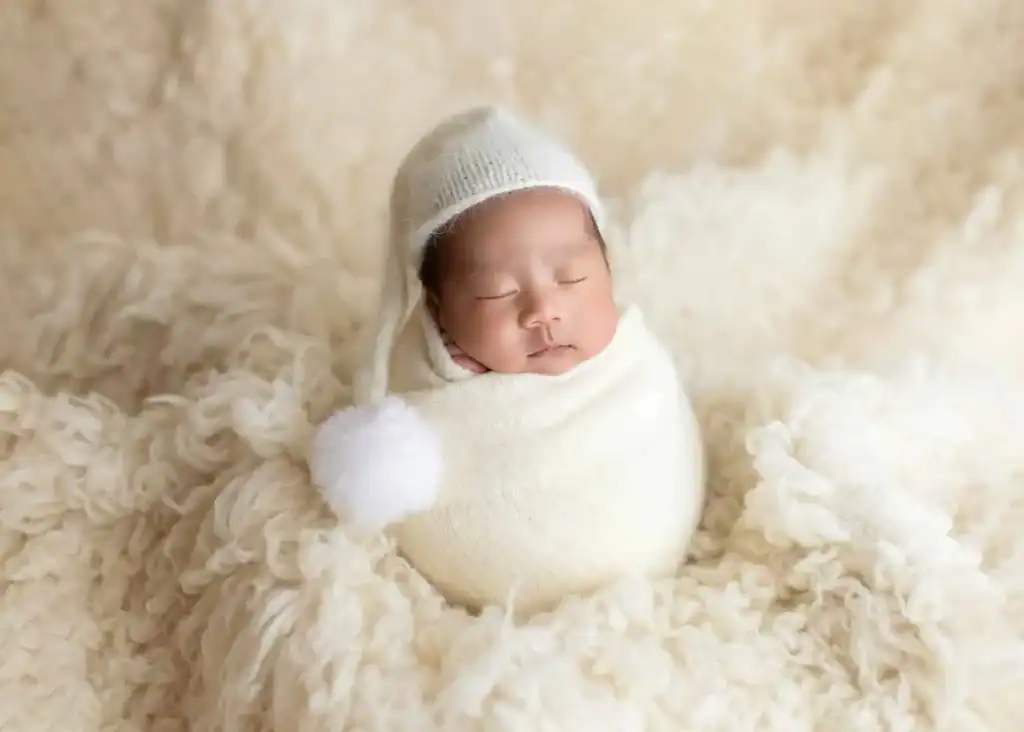 Minimalist newborn portrait with baby lying on a white posing fabric.