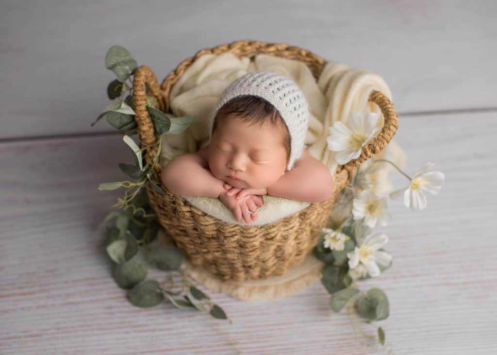Custmized newborn photo with baby posed on a cream-toned blanket.