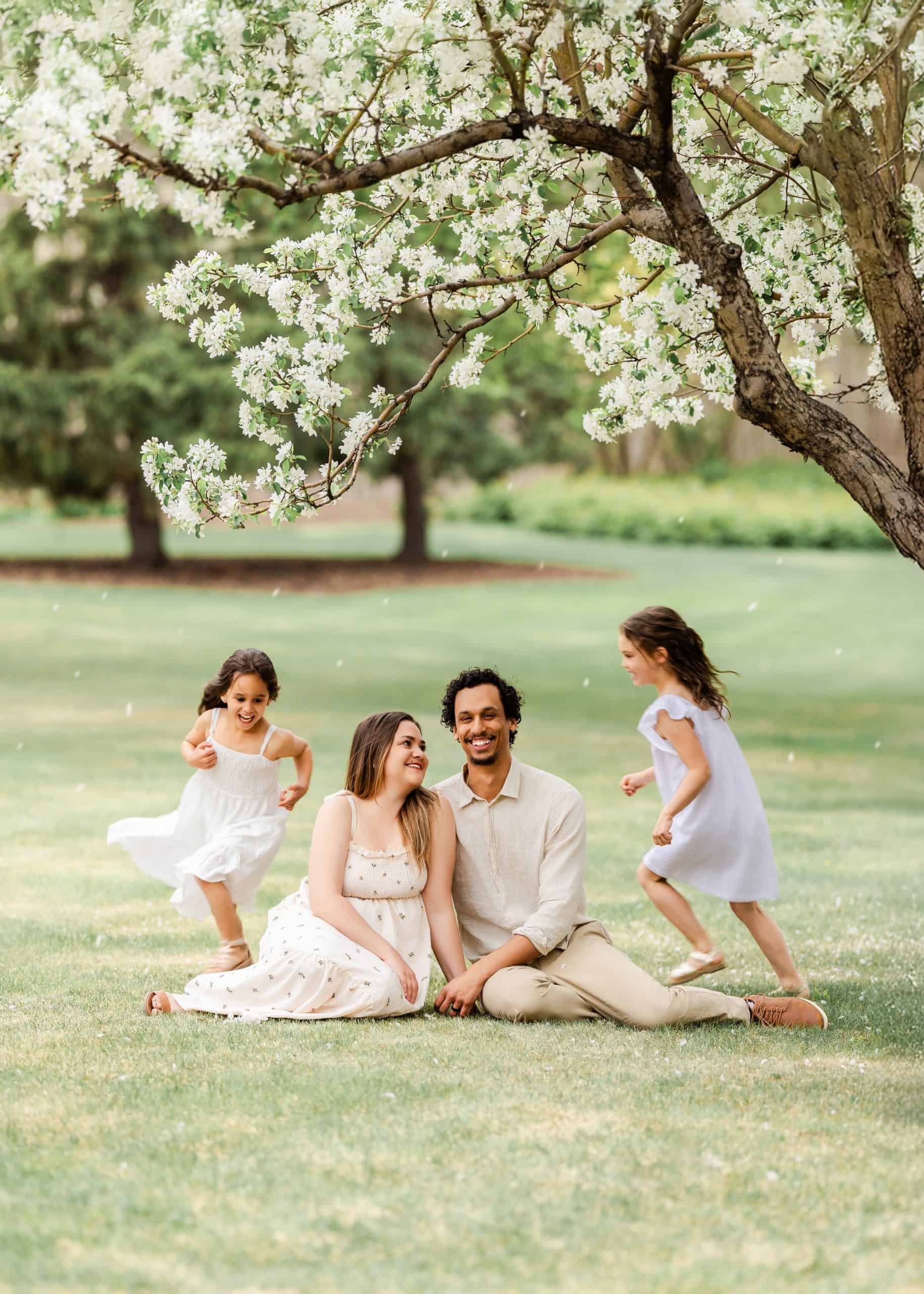 Family of four hugging during spring for outdoor family session at legislation buiding in Edmonton