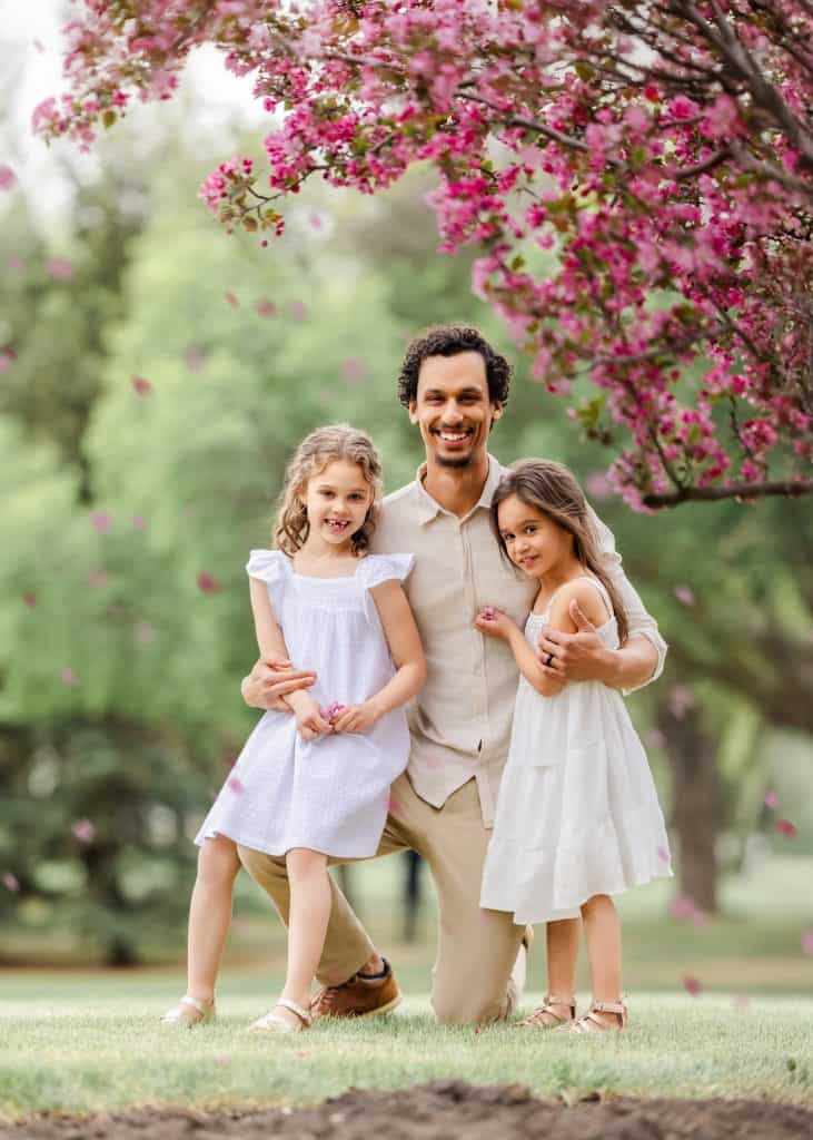 Dad hugging daughters tightly during a quiet moment in a family photoshoot in Edmonton
