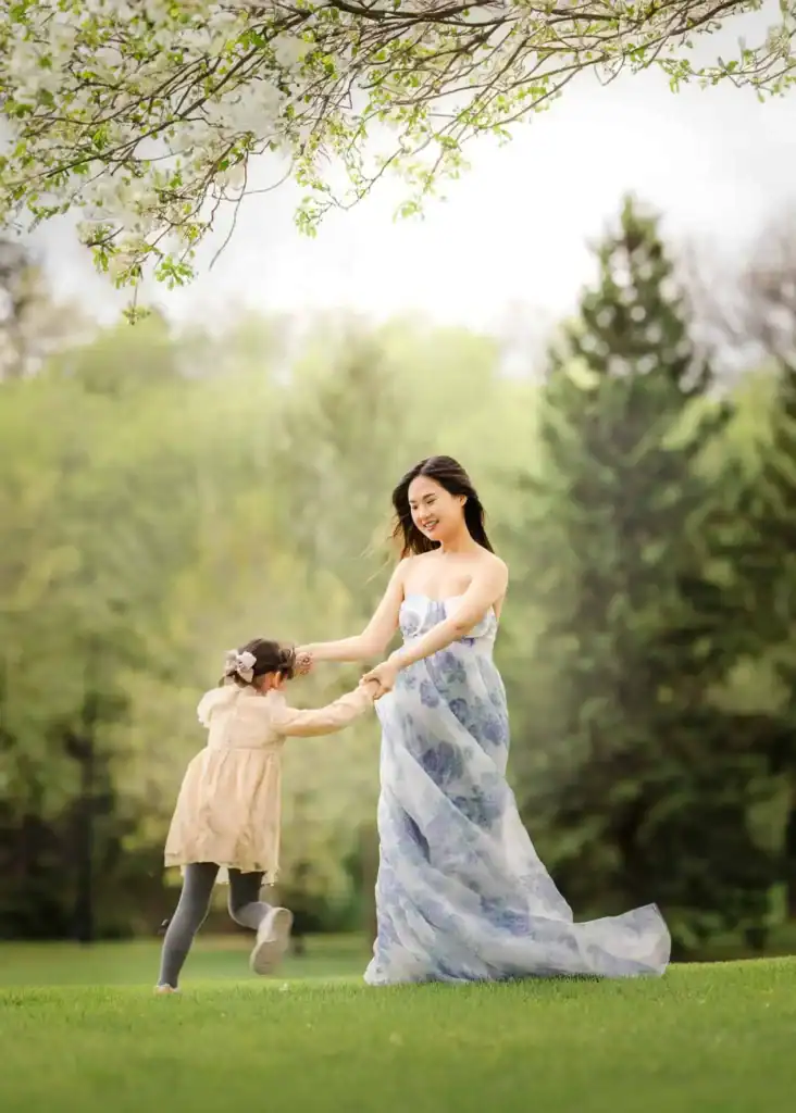 Mom spinning around while holding her toddler during an outdoor family photoshoot in Edmonton.