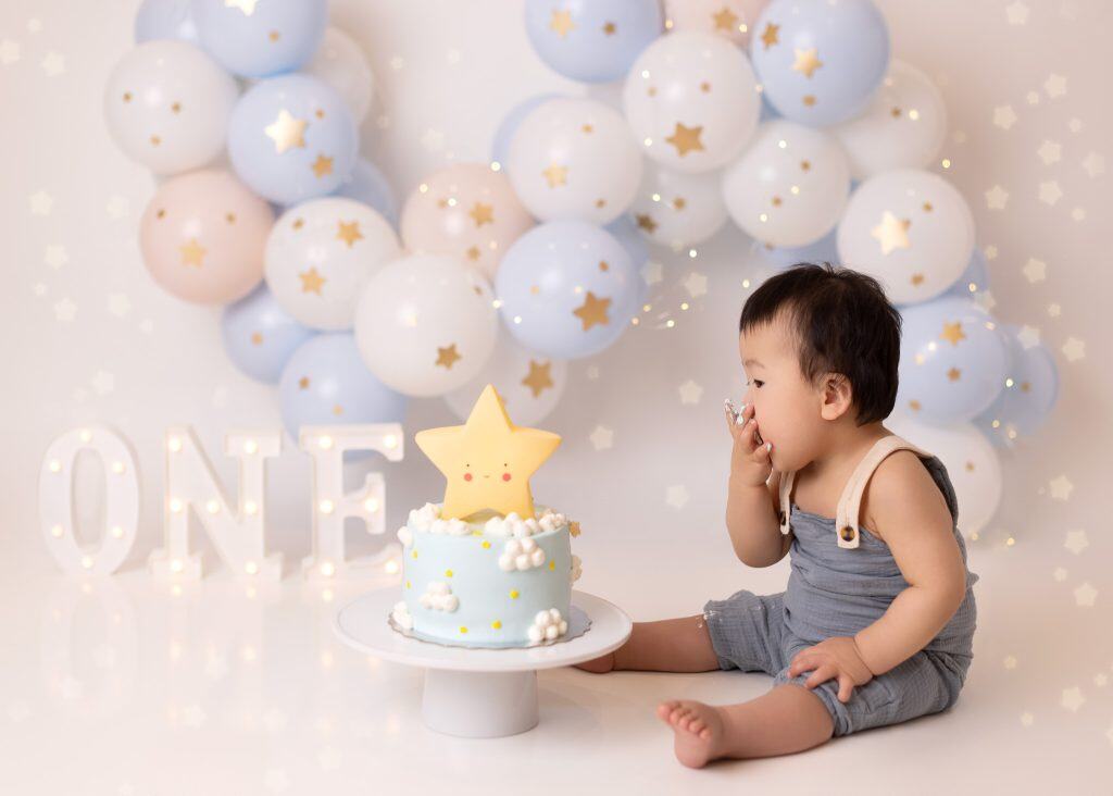 Sky-themed cake smash with soft blues, starts, and a cake shaped like the star for a baby boy’s birthday photoshoot.