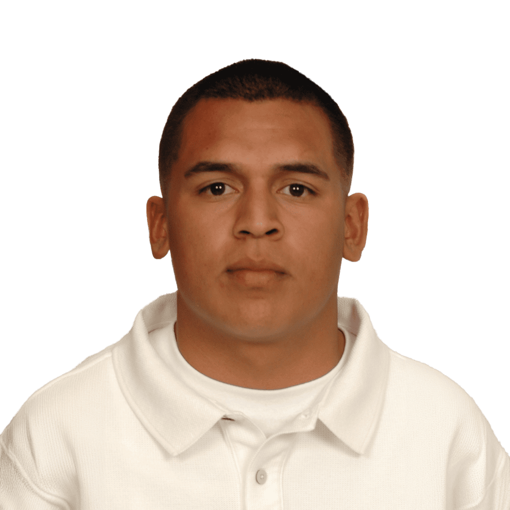 Young male football player in white jersey, focused and serious, on field.