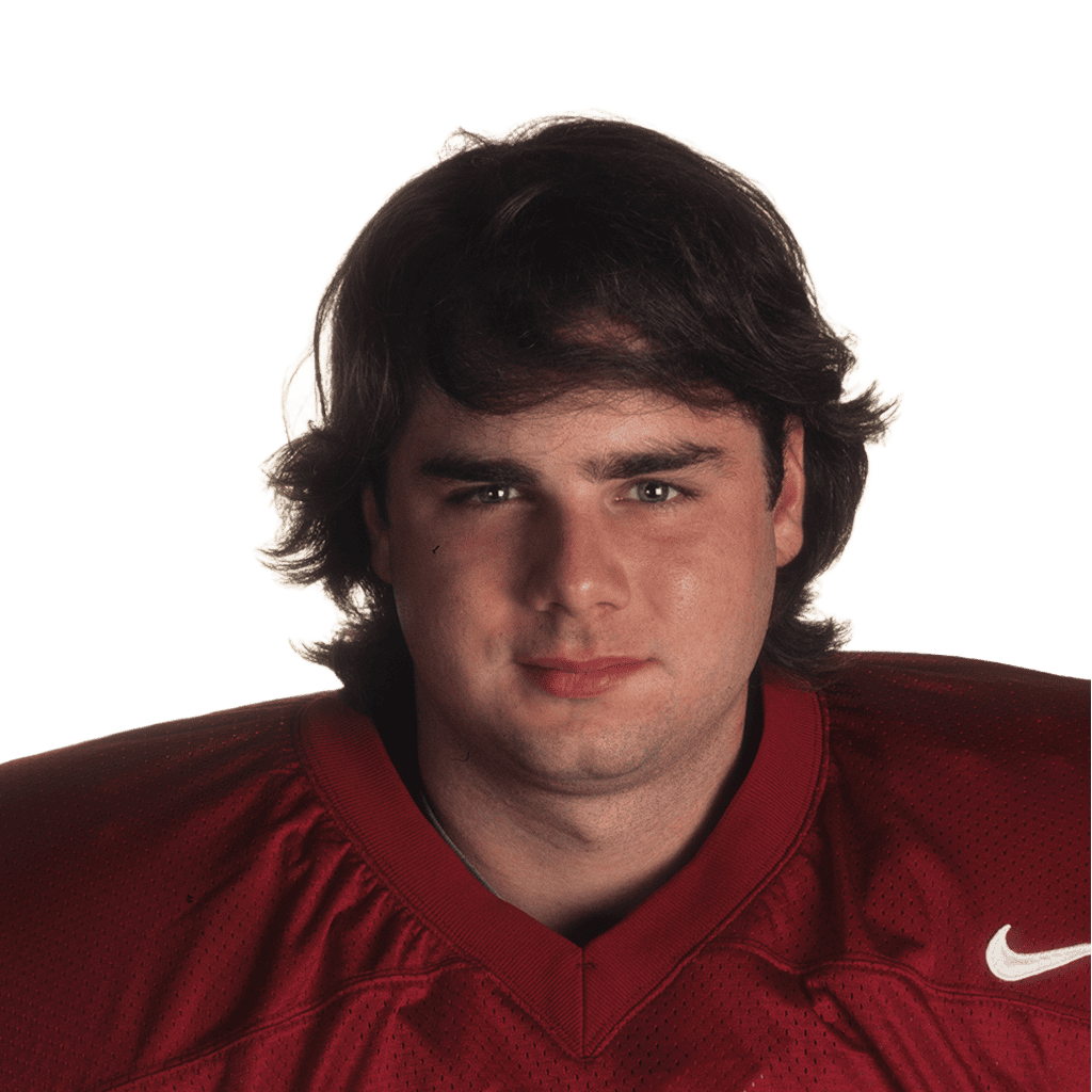 Young male football player in red jersey looking at camera.