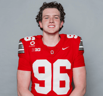 Young football player in red jersey smiling for the camera.