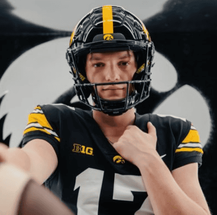 Football player in black and yellow uniform wearing helmet, taking a selfie.