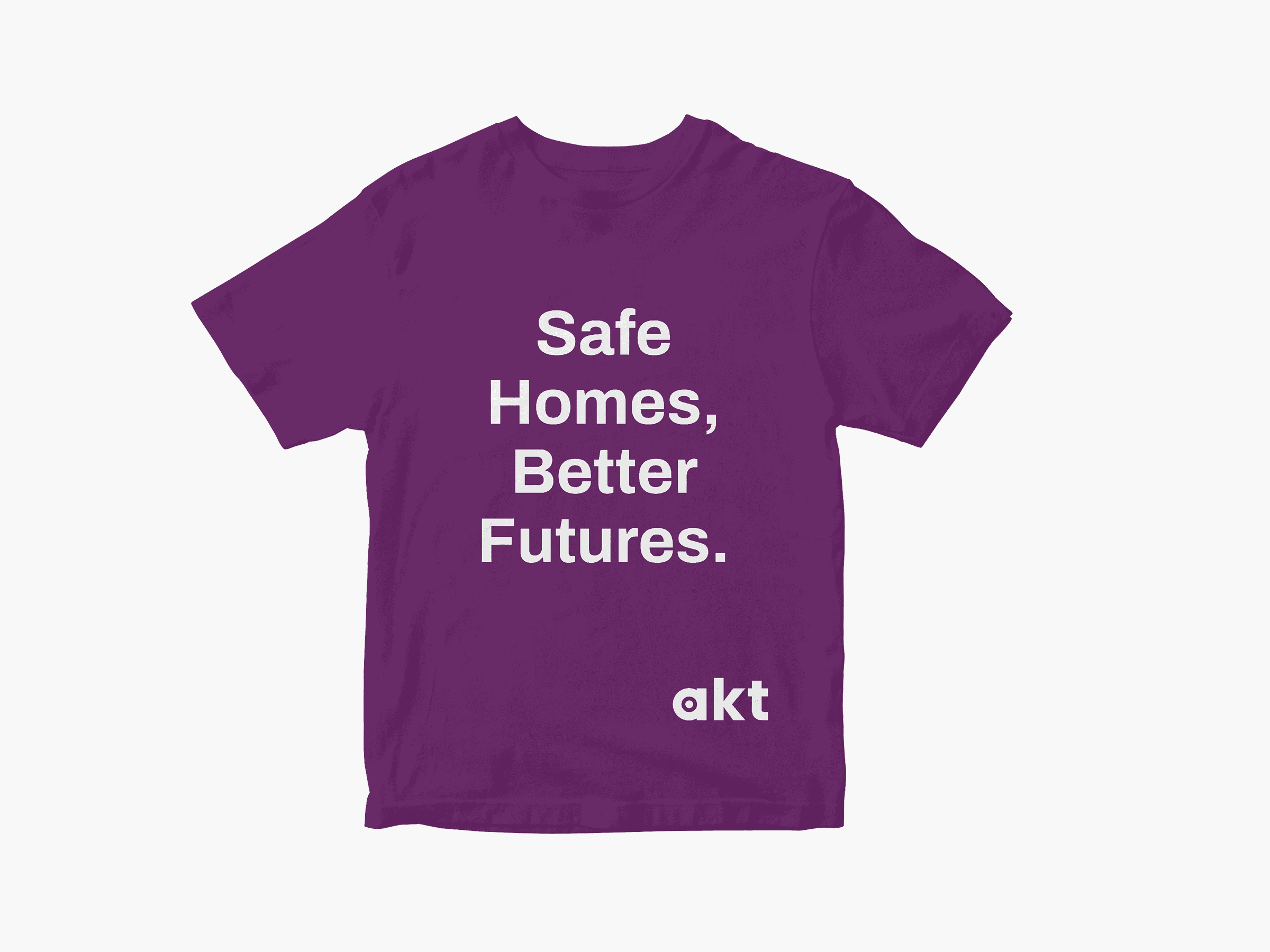 Purple T-shirt featuring bold white text saying ‘Safe Homes, Better Futures.’ with the akt logo in the lower right corner.