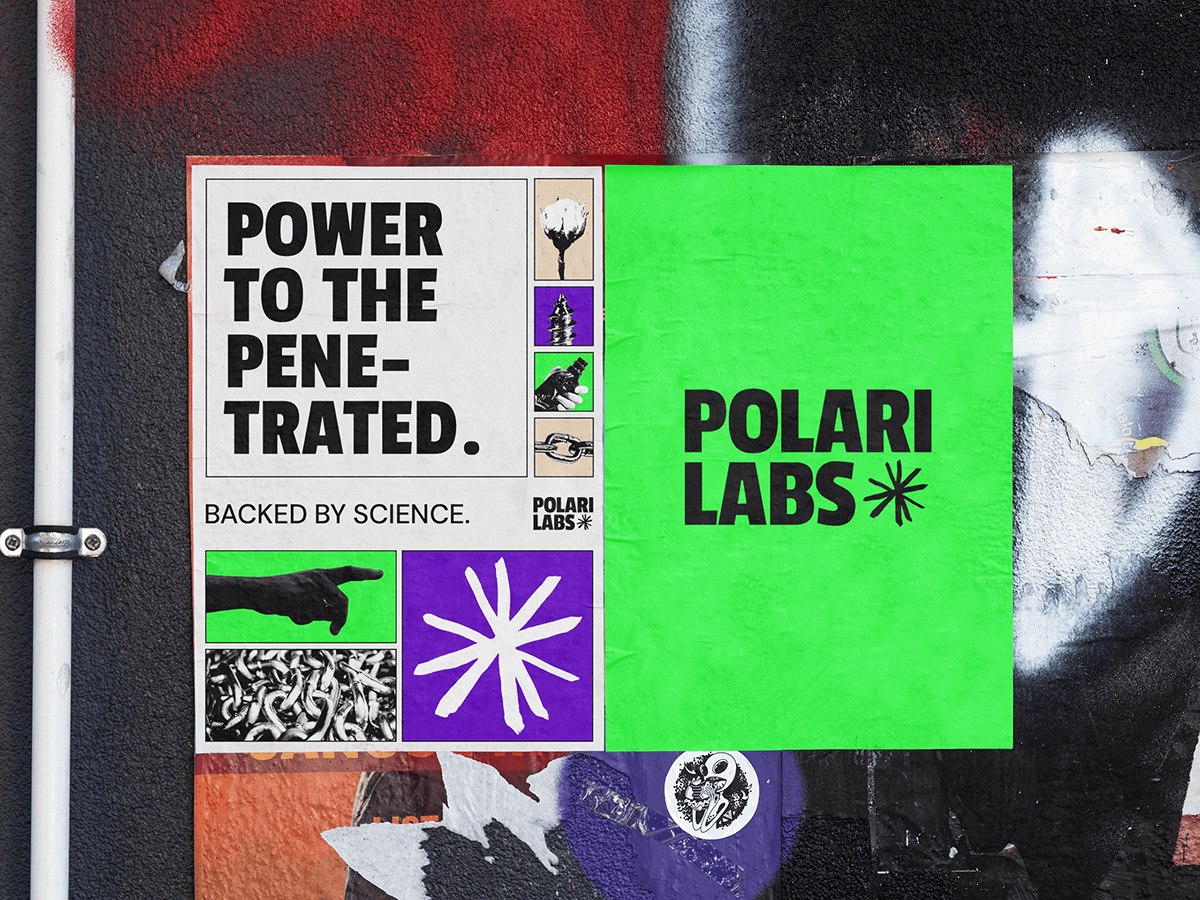 A vibrant poster on a textured wall displays the text Power to the Penetrated. Backed by Science. Accompanying this are small images including planets, a hand, and abstract designs. The right side of the poster is bright green, featuring POLARI LABS in bold black letters alongside an asterisk symbol.