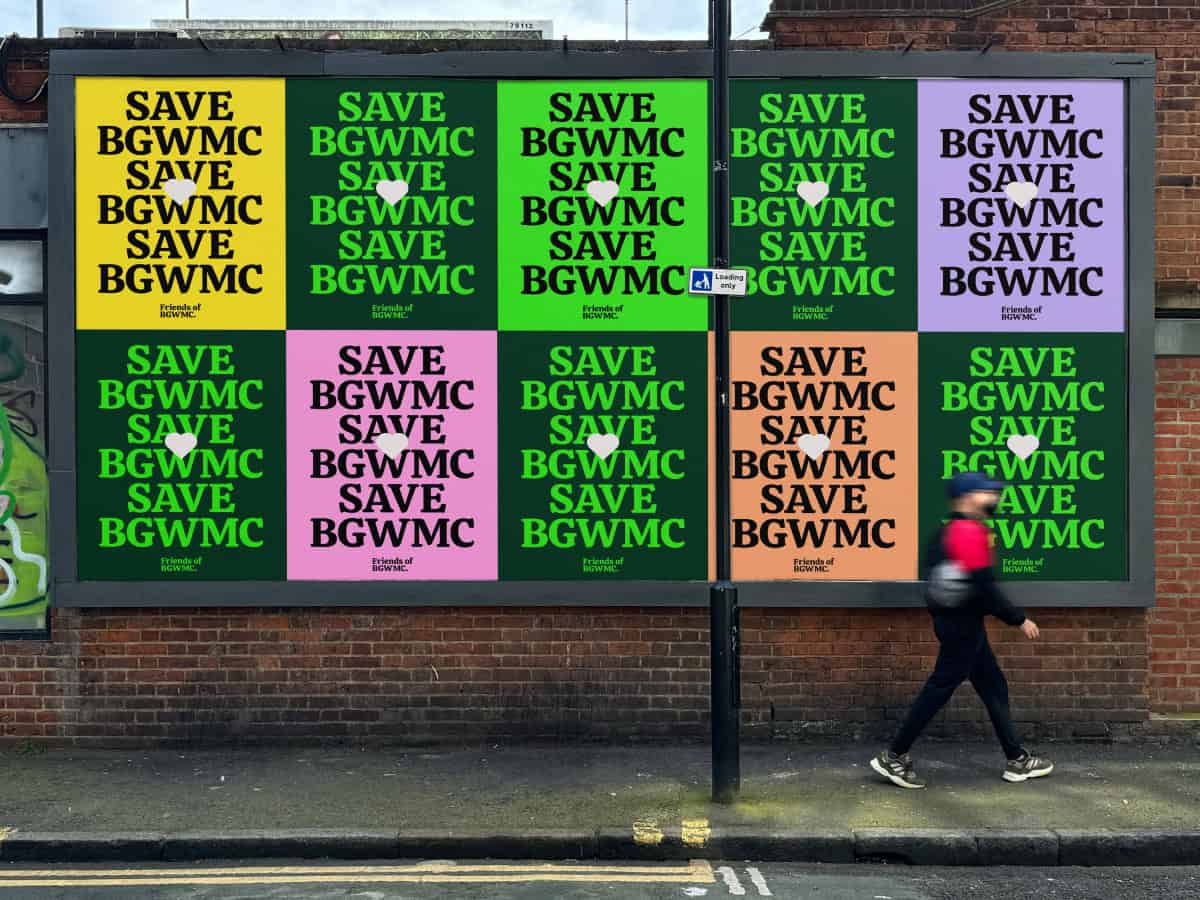 A person wearing a red hat walks past a large billboard on a brick wall. The vibrant display showcases colourful posters with the message SAVE BGWMC in bright shades of yellow, green, pink, orange, and purple. These colours highlight support for the cherished Bethnal Green Working Mens Club.