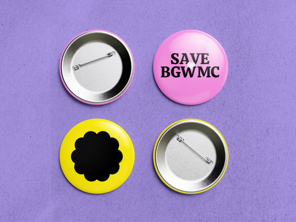 Four buttons on a purple background: two pink with SAVE BGWMC printed on the top. One is face up and the other shows the pin. Two are yellow with a black scalloped pattern, likewise, one is face up while the other displays the pin.