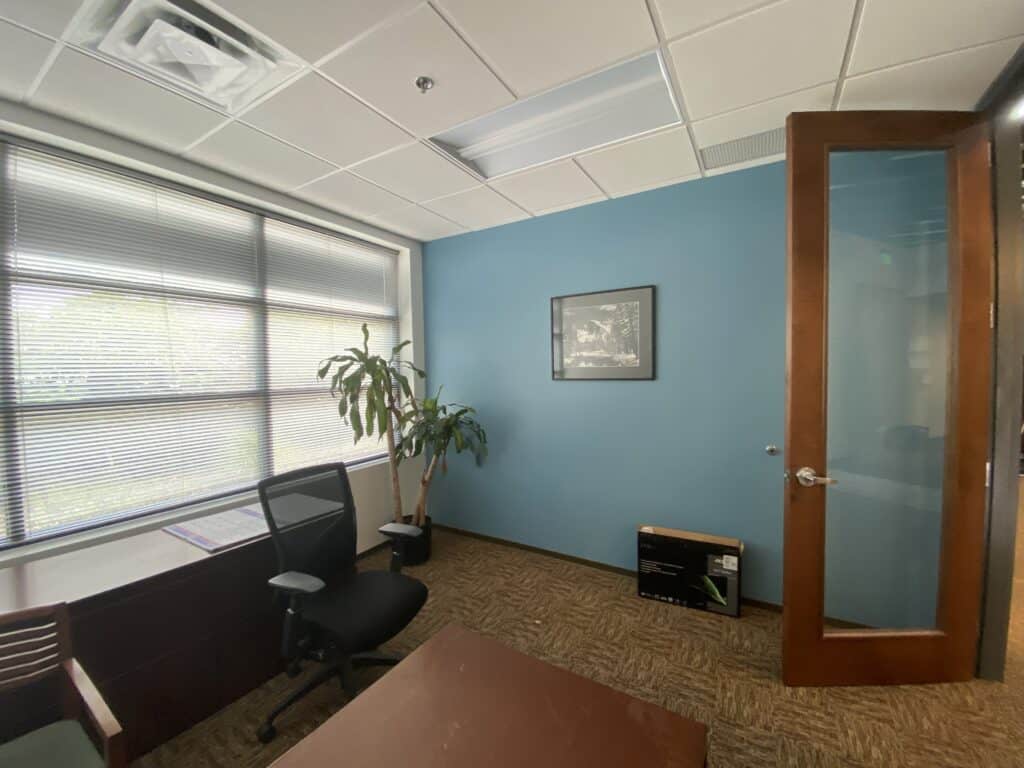 Executive office with commercial carpet, desk setup, and glass partition door - office build-out Dunwoody