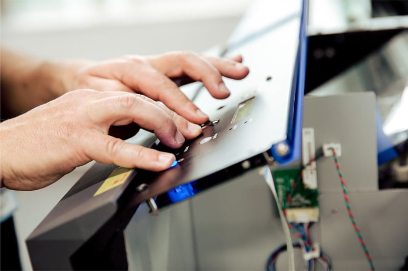 Alt: Persona operando una impresora de plotter para impresión de vinilos y gráficos en un entorno profesional.