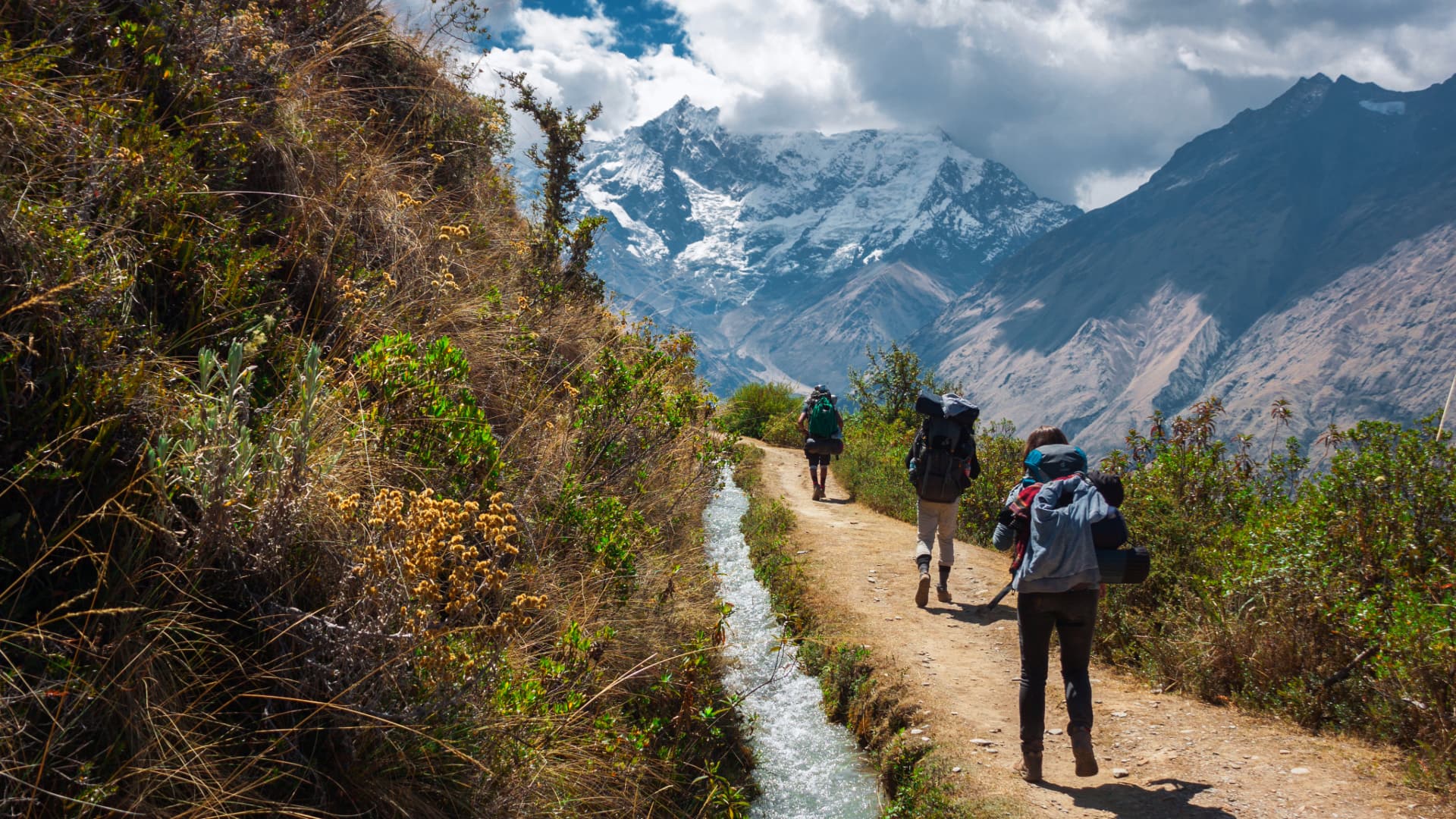 A group of hikers ascending steep slopes, with the imposing Salkantay mountain in the background.