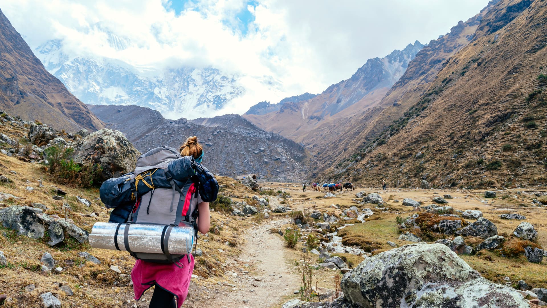 A tranquil Andean lake reflecting warm sunset hues against towering mountain silhouettes.