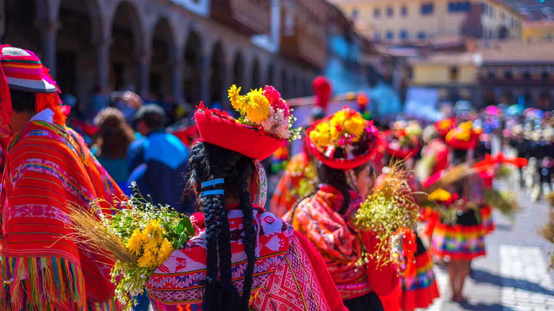 Women dancing in traditional Cusco attire with colorful skirts and hats, showcasing Andean culture.