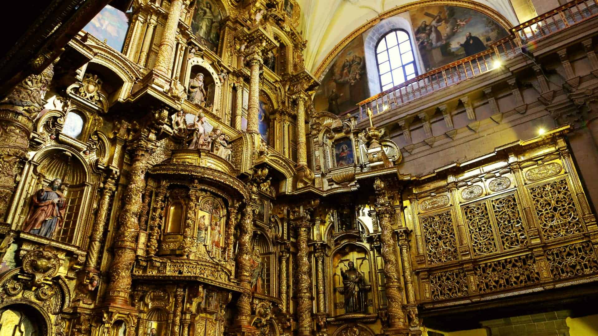 A stunning golden altarpiece with intricate carvings and religious figures inside a historic church