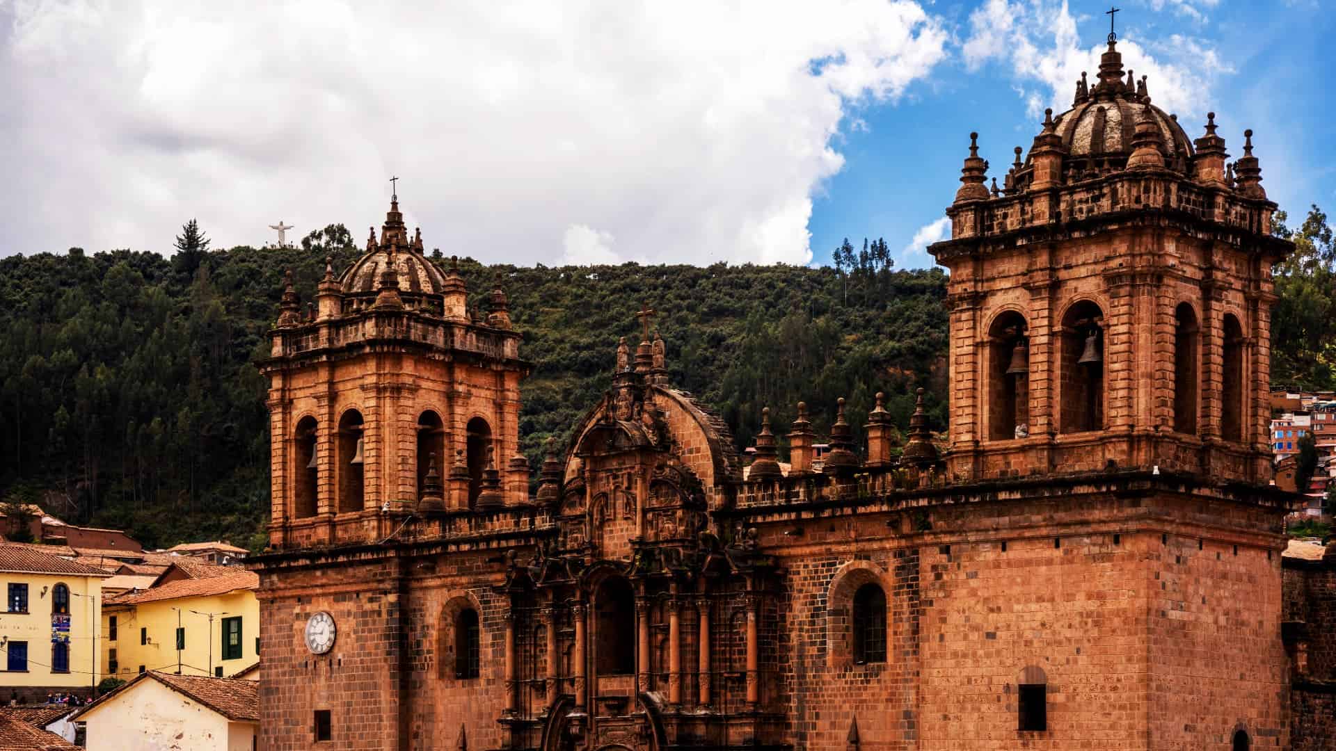 A stunning view of the historic Cusco Cathedral with the green Andean mountains in the background.