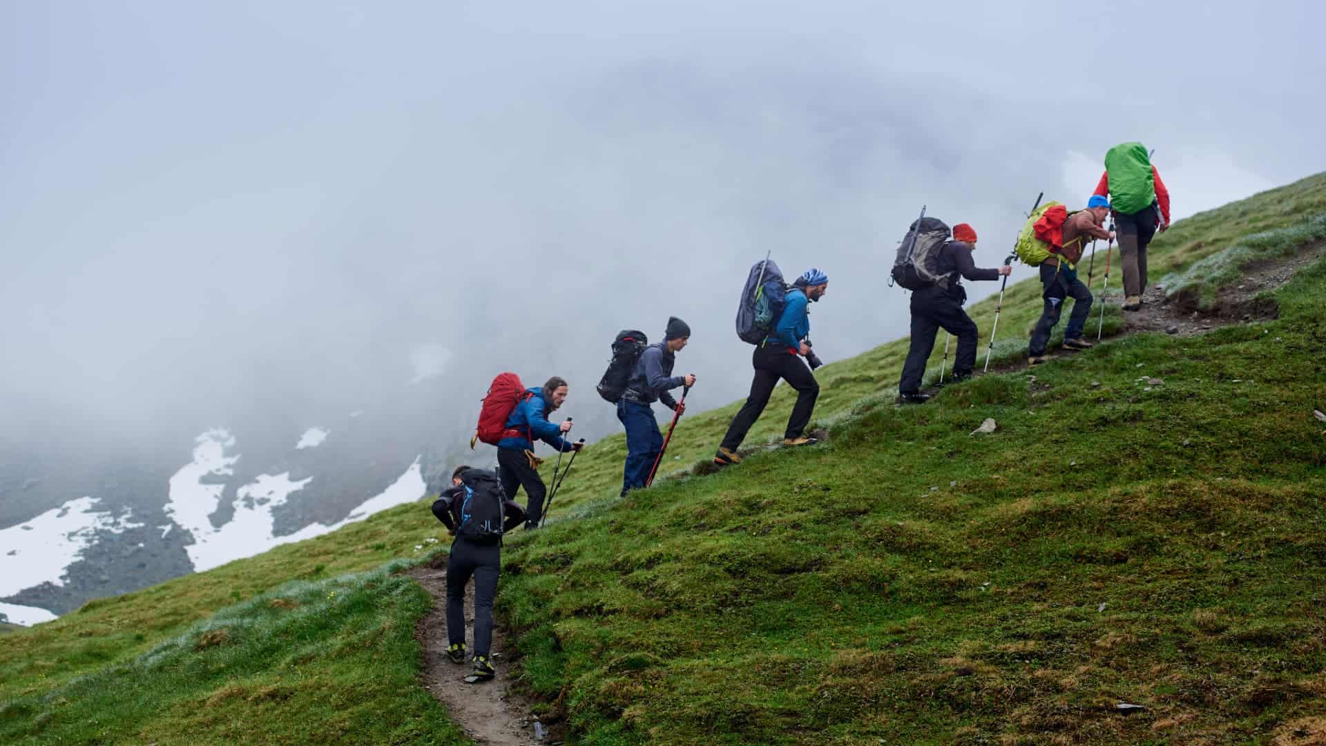 Group of hikers climbing a misty, high-altitude Andean mountain pass with trekking poles and winter gear - Magical Cusco Travel Agency