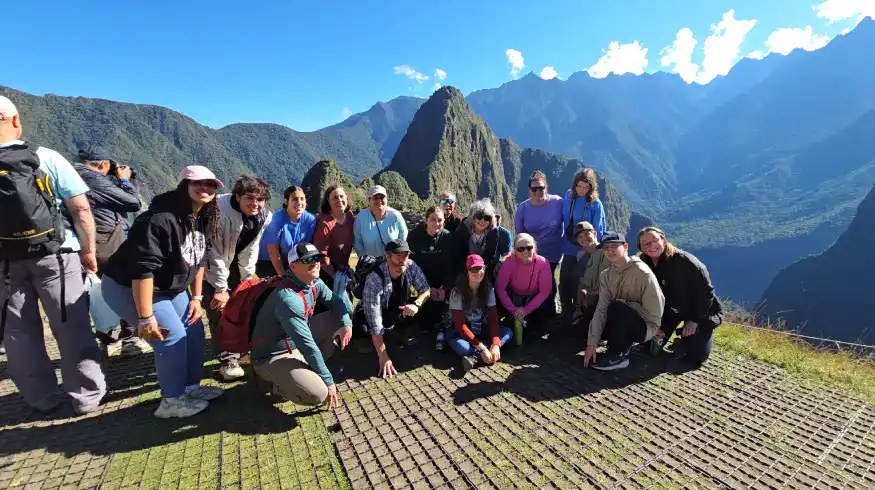 Group of tourists exploring Machu Picchu with guide in the Andes mountains.