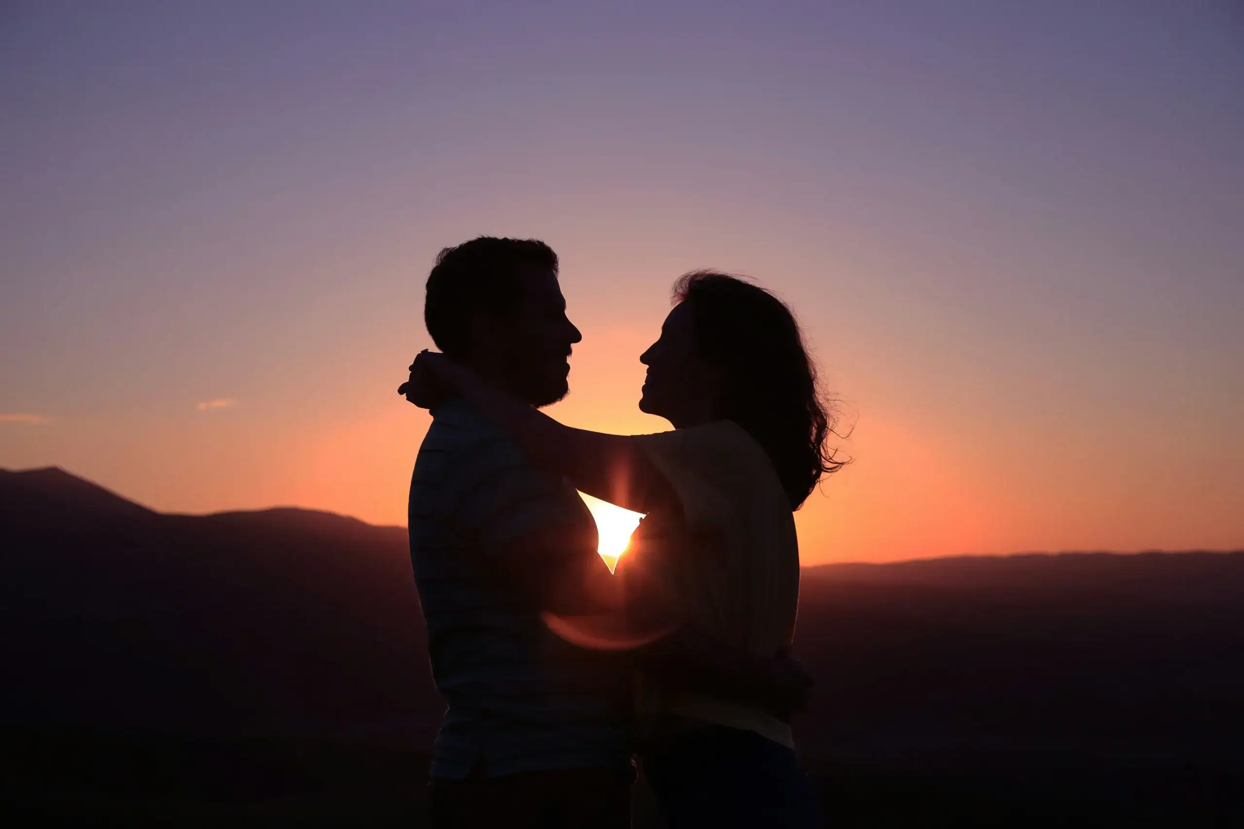 Romantic couple embracing during a golden sunset.