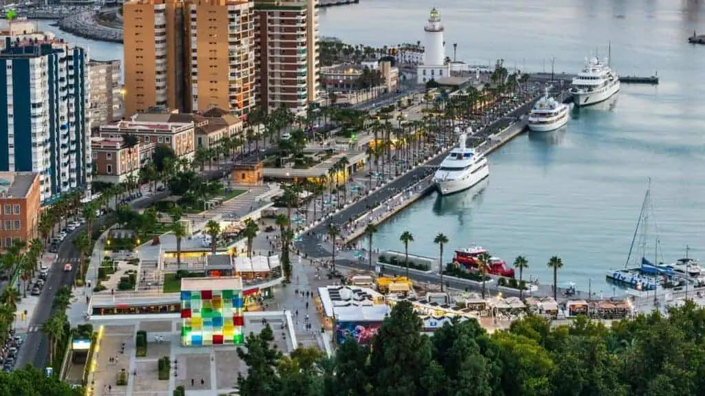 Vista panorámica del paseo de Muelle Uno en Málaga, con terrazas, tiendas y la Giralda al fondo.