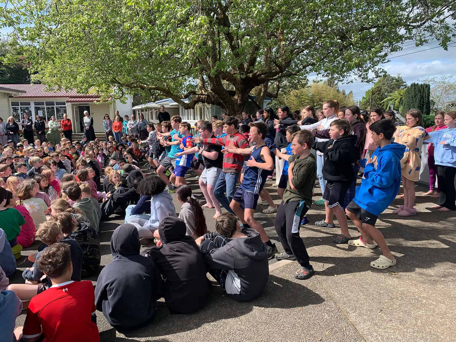Children performing haka at Mangorei School outdoor assembly, community event in New Zealand.