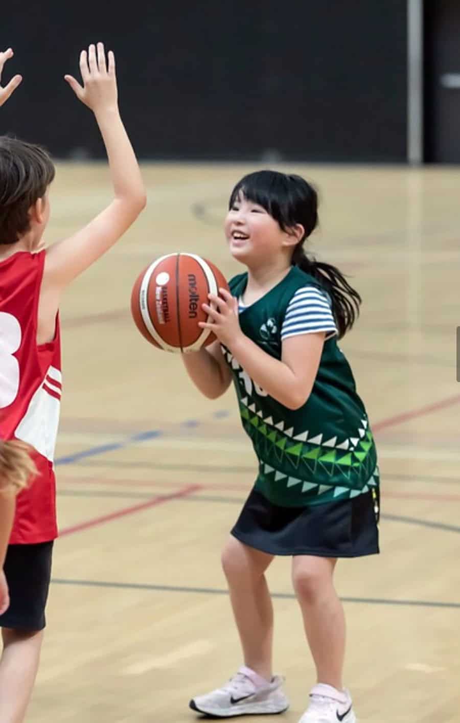 Basketball game at Mangorei School in New Zealand, children playing basketball in gym.
