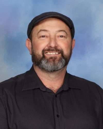 Friendly male teacher at Mangorei School in New Zealand, smiling in a professional portrait.
