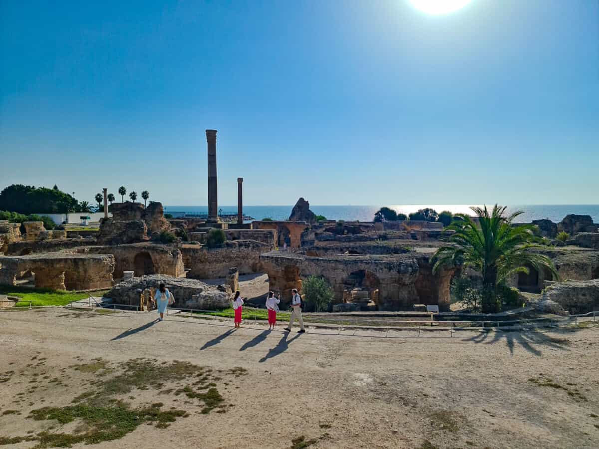 Tourists exploring the Roman ruins of the Antonine Baths in Carthage, Tunisia, with sea views—one of the top historical landmarks in Tunisia.