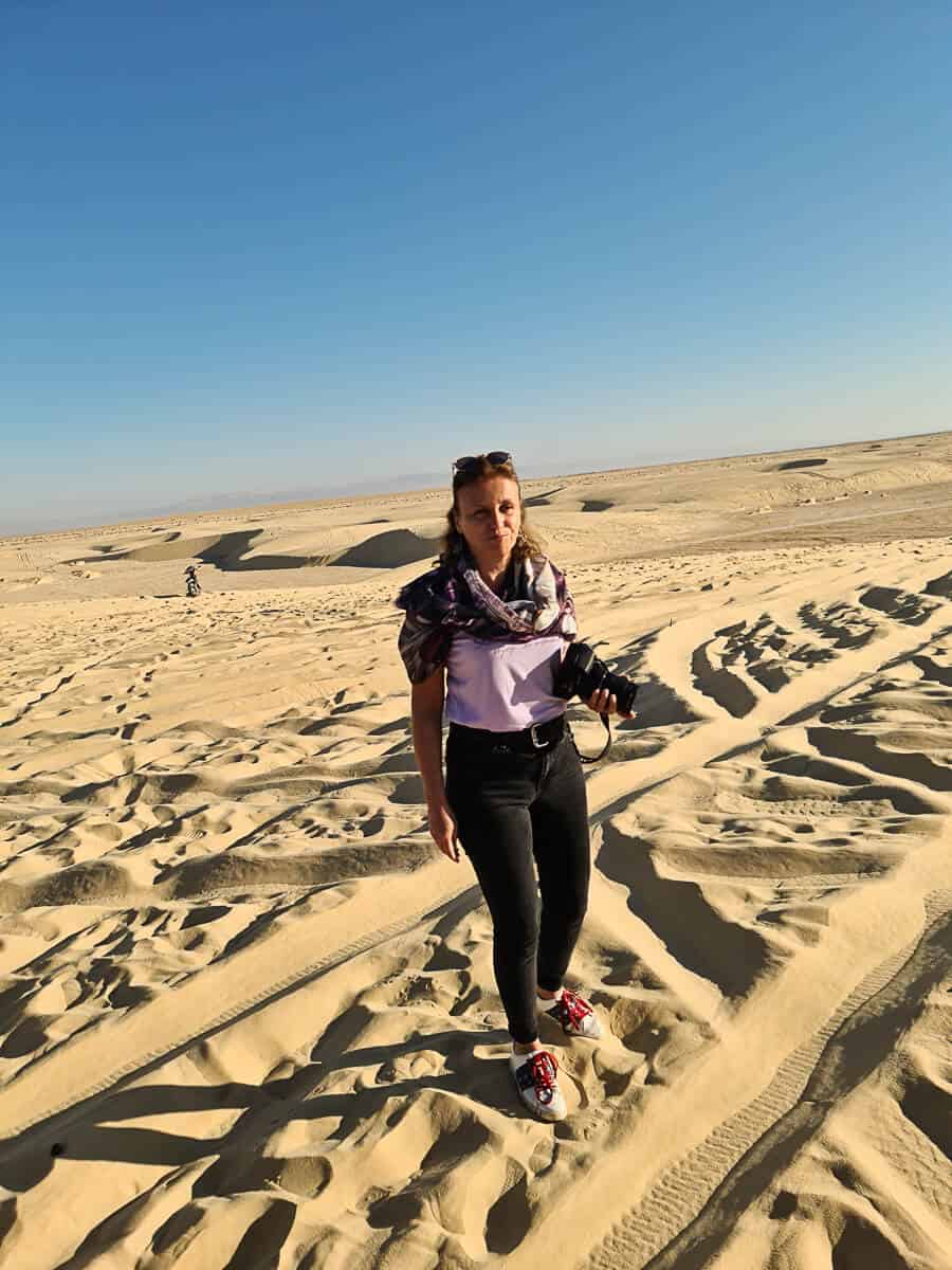 Maria Dol of Map and Camera walking across the sand dunes of the Tunisian Sahara Desert, one of the most breathtaking natural places to visit in Tunisia for photography and adventure.