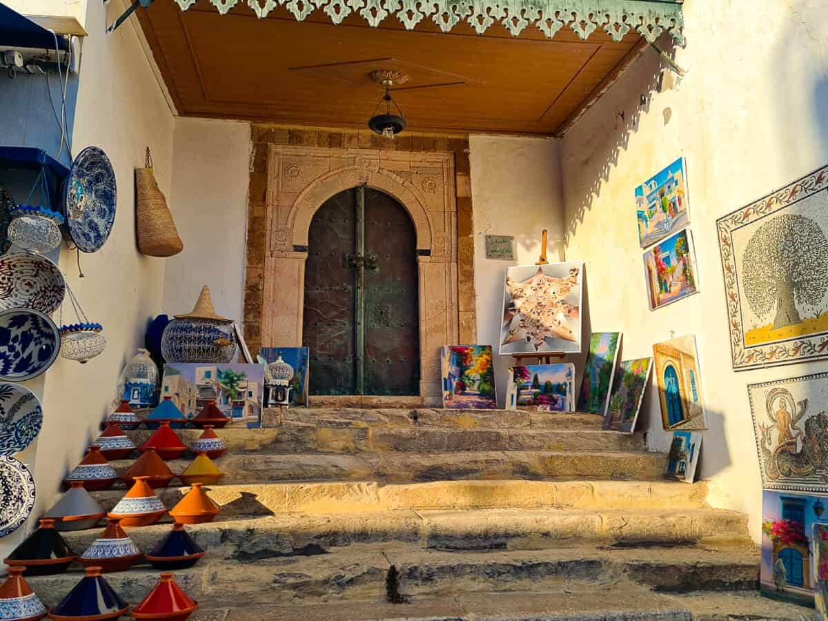 Colorful paintings and traditional pottery displayed on the steps of an art gallery in Sidi Bou Said – a coastal town known for its artistic vibe and one of the best places to visit in Tunisia.