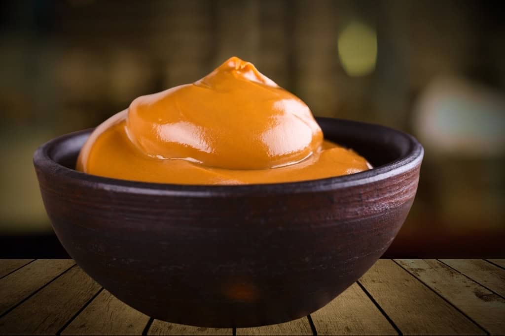 A bowl of rich, creamy dulce de leche, a classic Argentine treat and must-buy edible souvenir from Argentina. Perfect for gifting or enjoying as a taste of Argentina at home.