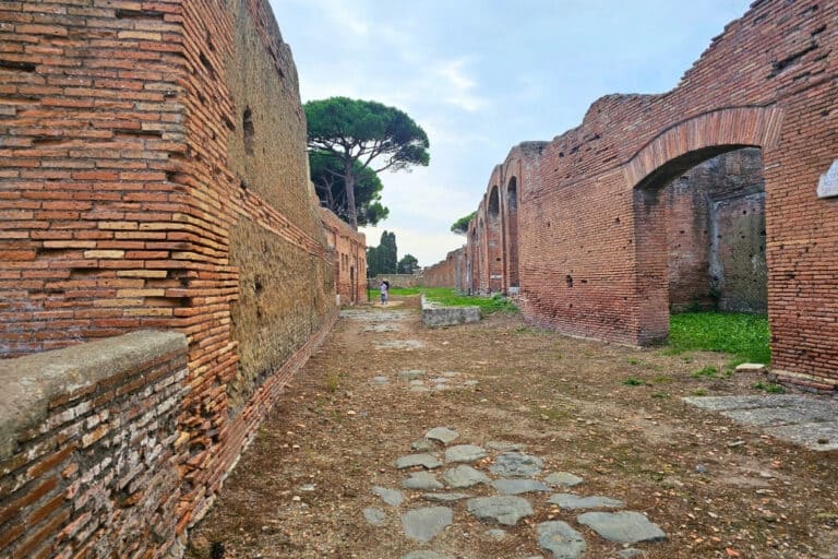 Cobblestone street lined with Roman ruins in Ostia Antica, a key highlight when visiting Ostia Antica.