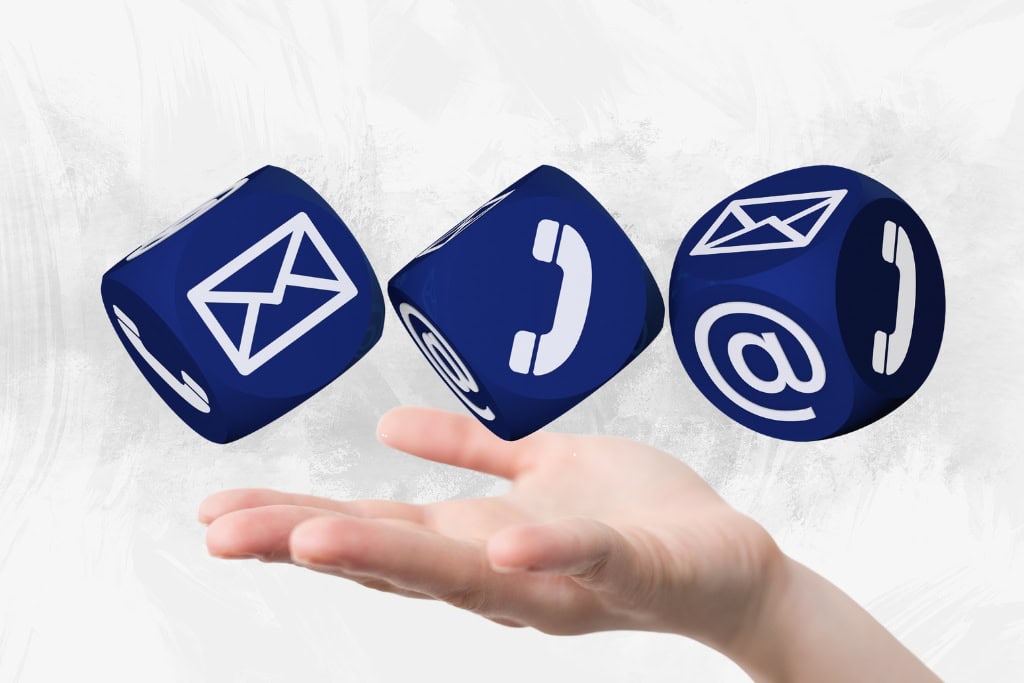 Floating blue cubes displaying email, phone, and contact me icons above a hand, symbolizing communication and connectivity options.